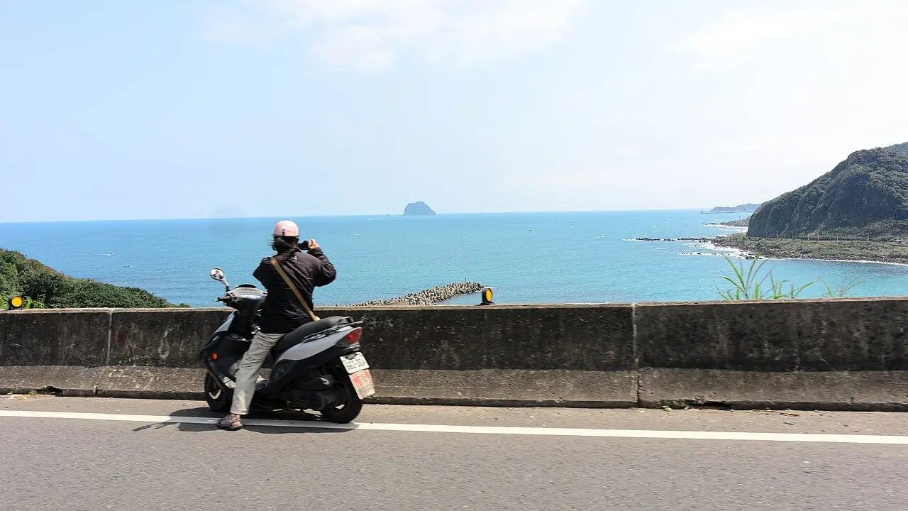 騎速克達停在台灣海岸公路旁的騎士背影